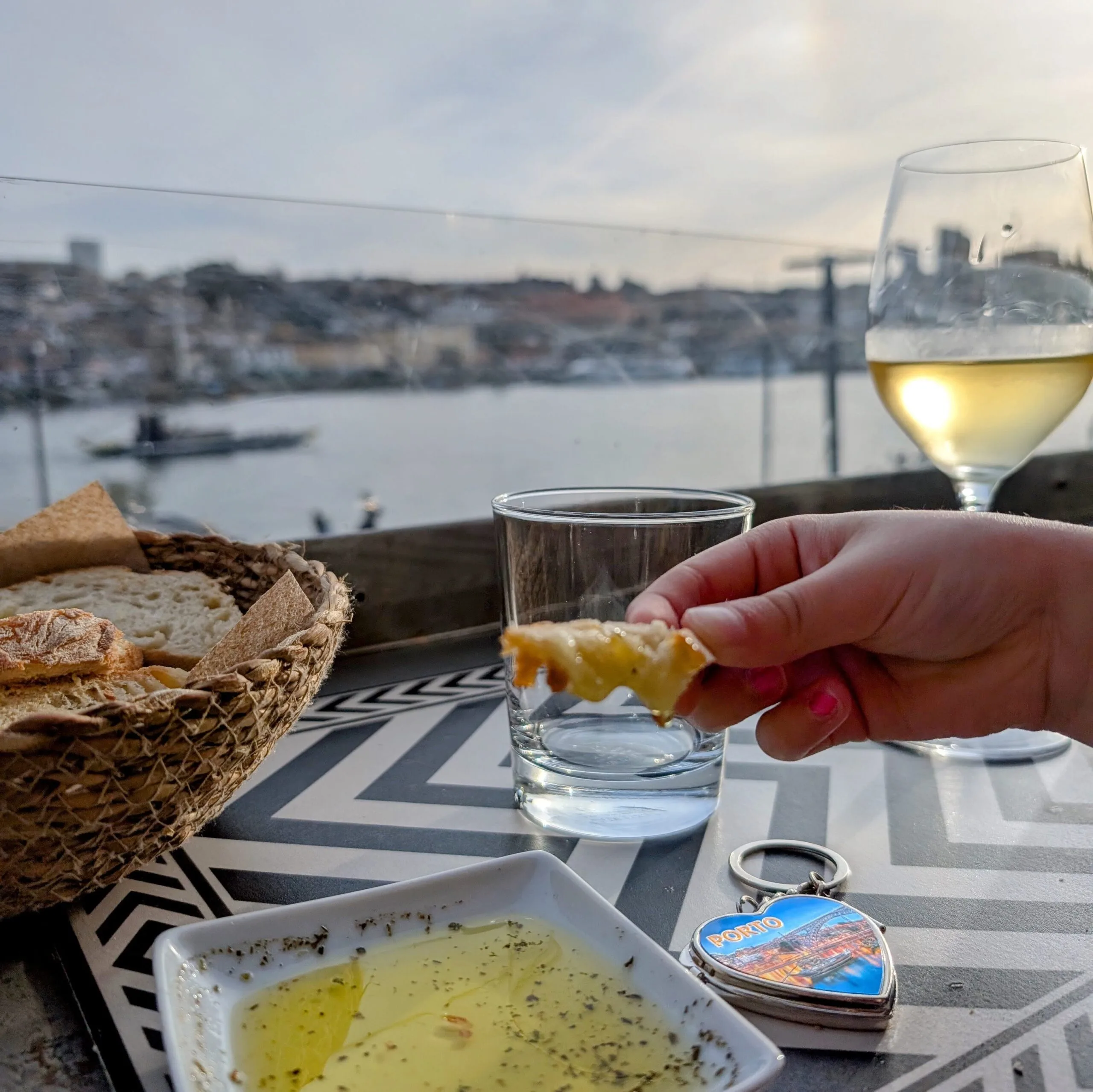 wine and bread in porto A scenic riverside dining moment in Porto with a glass of white wine, fresh bread, and olive oil, capturing the essence of Portuguese cuisine.