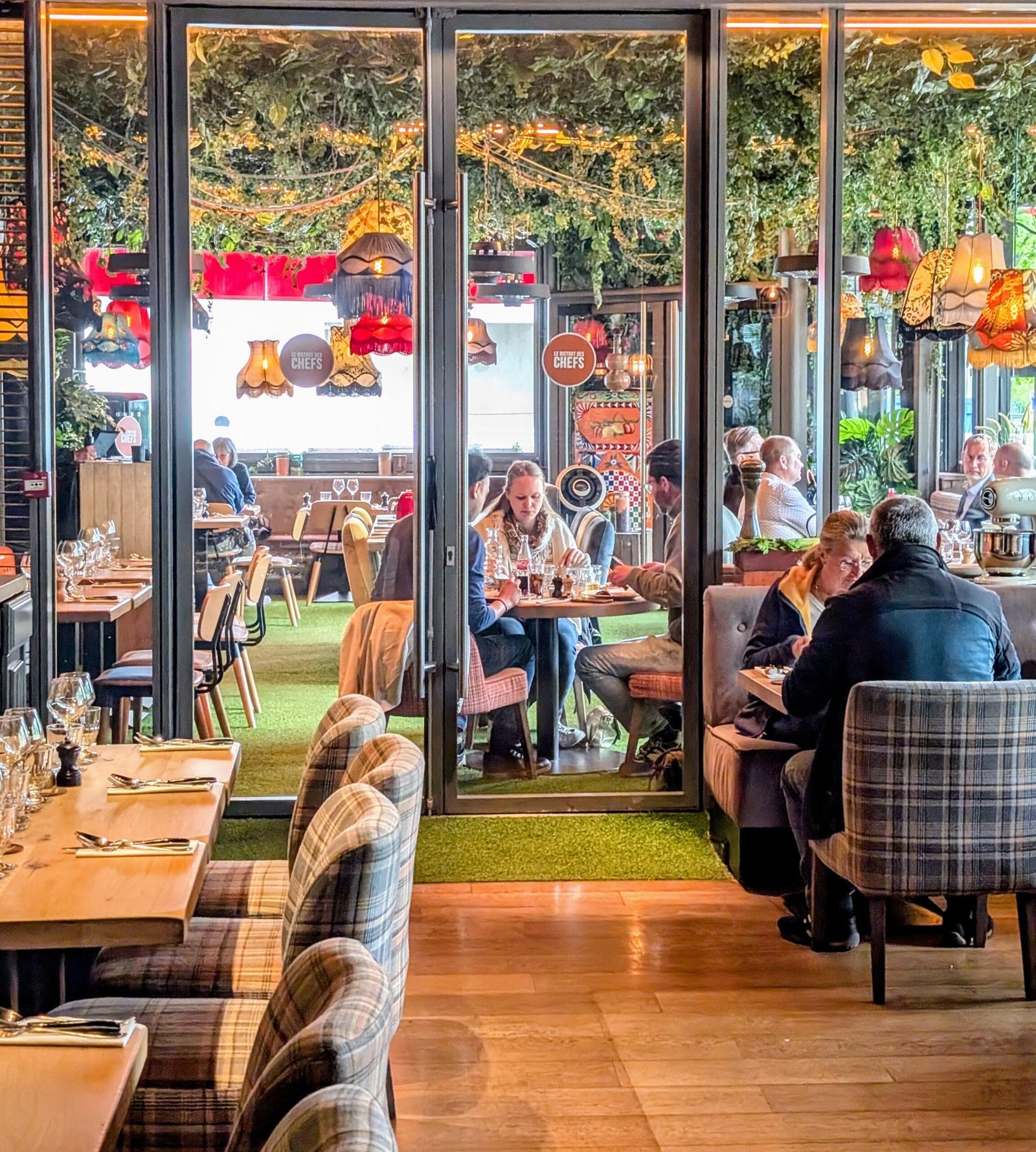 Bistro des Chefs Review: Where Top Chef Hype Meets Instagram Reality in Suresnes 1 Interior of Bistro des Chefs in Suresnes with eclectic decor, hanging lamps, leafy ceiling, and diners enjoying lunch in a colourful, family-friendly setting