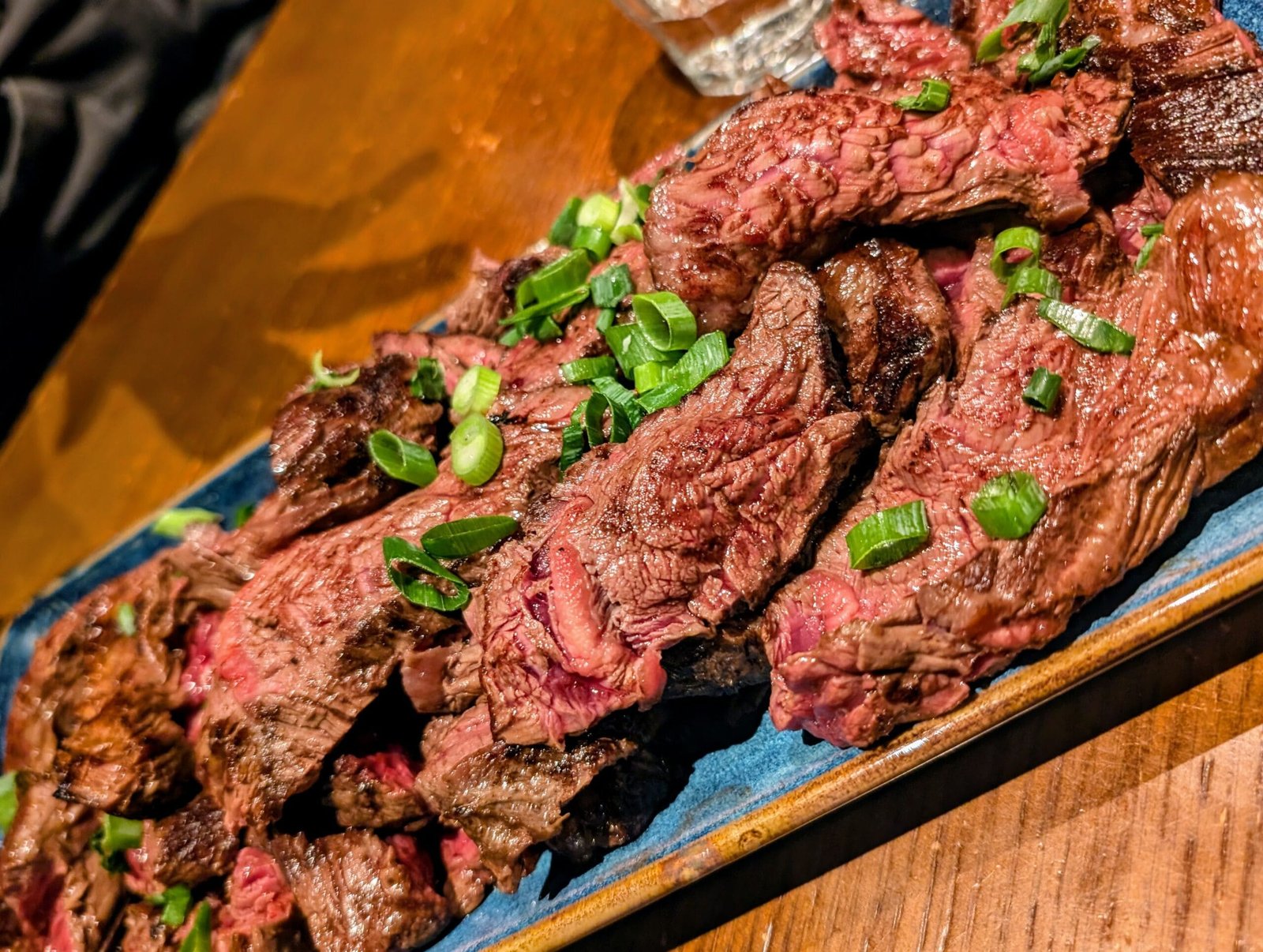 Les Foudres - Steak Grilled onglet steak served medium-rare at Les Foudres Paris, topped with chopped spring onions on a blue ceramic plate.