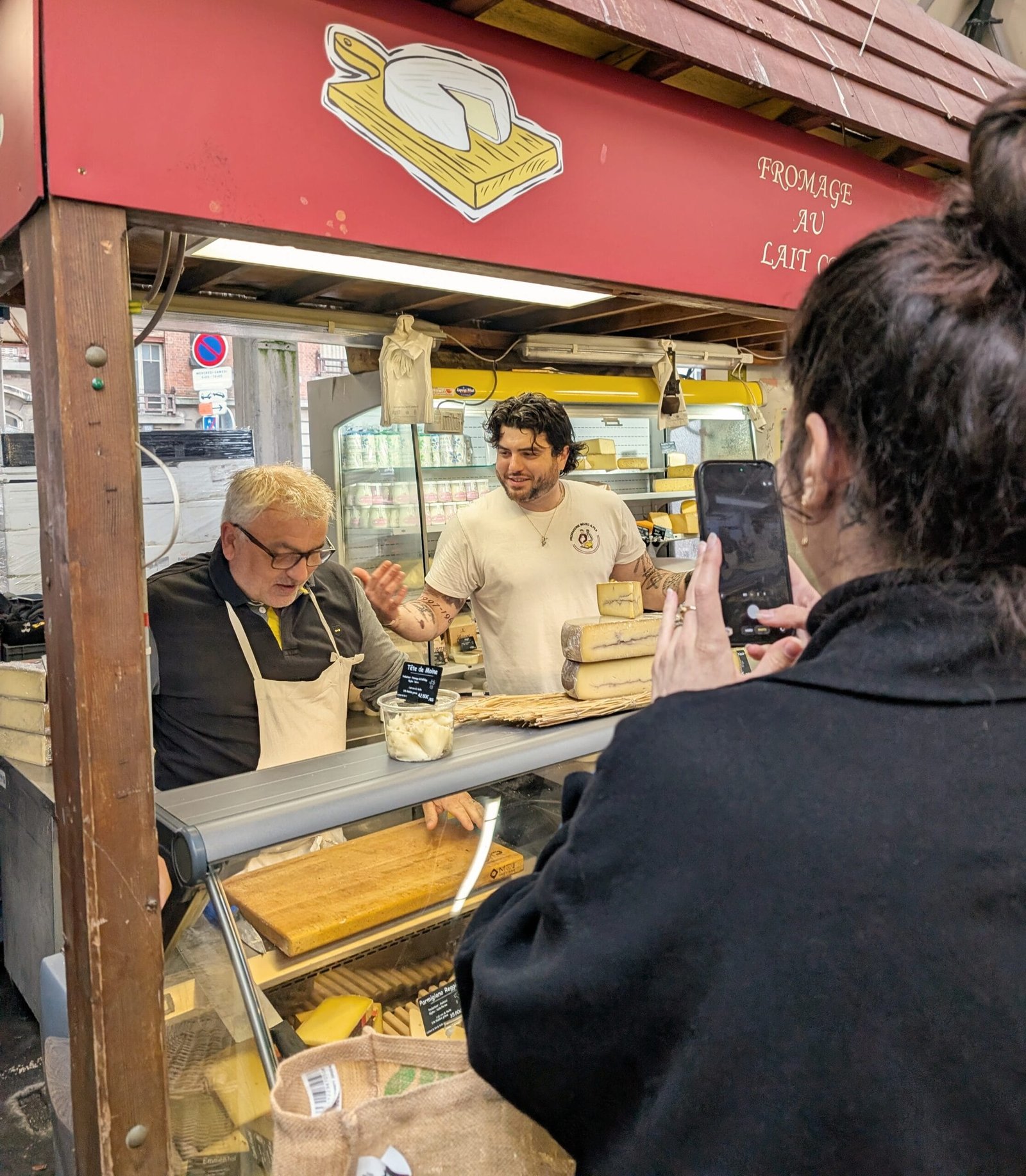 Local fromager at Boulogne-Billancourt market serving cheese to customers in Paris.