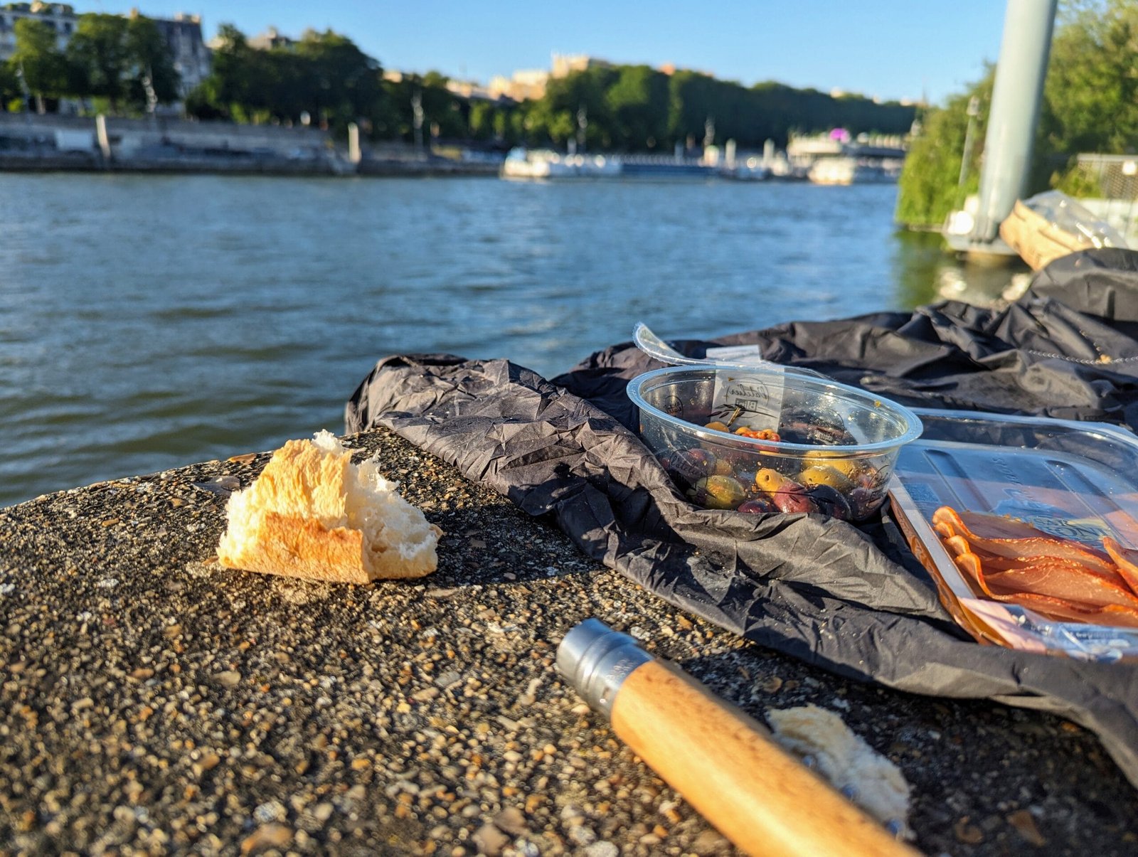 Paris picnic by the Seine with baguette, charcuterie and Opinel knife in summer